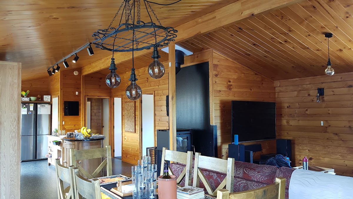 Timber lined room with a wrought iron chandelier and Edison globes